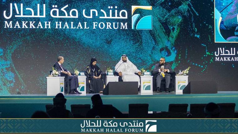 Raeesa Sya on a four-person panel at the Makkah Halal Forum, seated on stage in front of a large teal forum backdrop.
